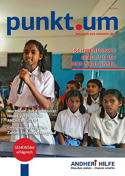 Titelbild des Magazins der ANDHERI HILFE: Mehrere indische Mädchen in einer Schulklasse. Ein Mädchen steht und spricht in ein Mikrofon
