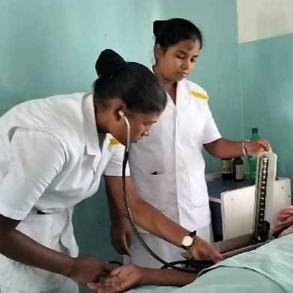 indische Krankenschwestern bei einem Patienten am Bett