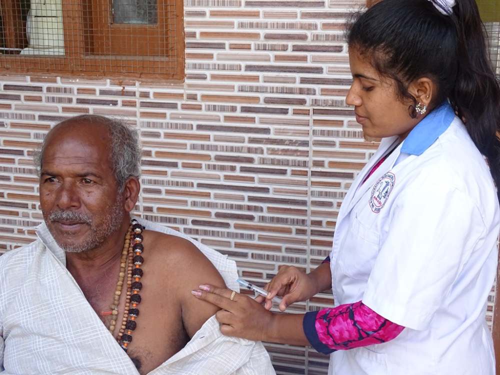 Junge Frauen in Indien: Eine Frau impft einen älteren Mann
