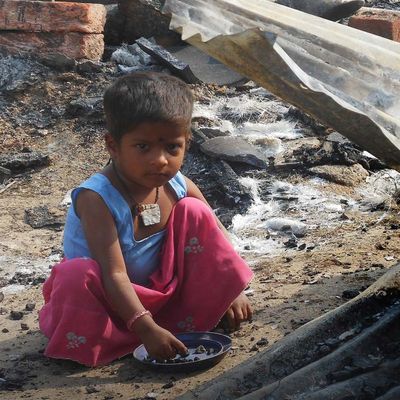 Kind sitzt in einem indischen Slum auf dem Boden