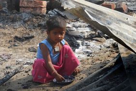 Kind sitzt in einem indischen Slum auf dem Boden