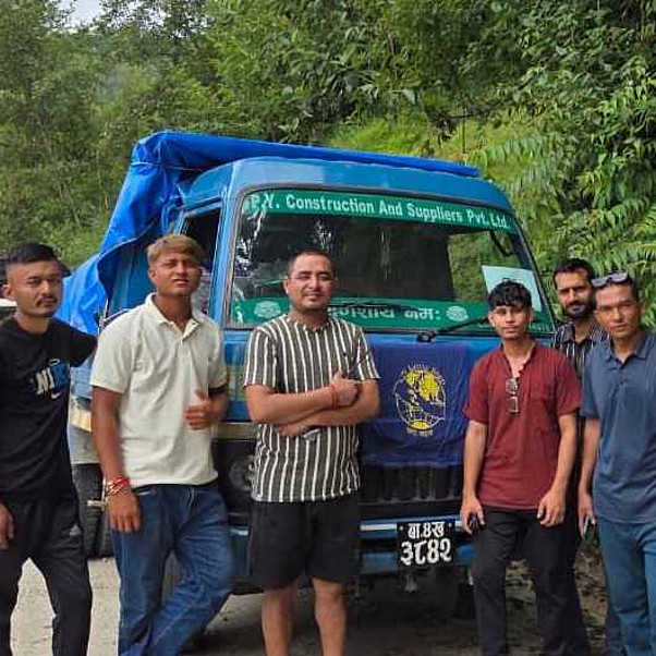Flut Nepal: Männer stehen vor einem LKW mit Hilfsgütern für die betroffenen Flutgebiete