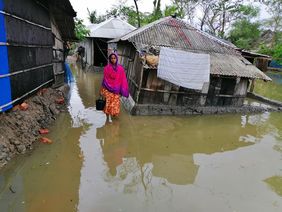 FRau steht in überflutetem Dorf in Bangladesch
