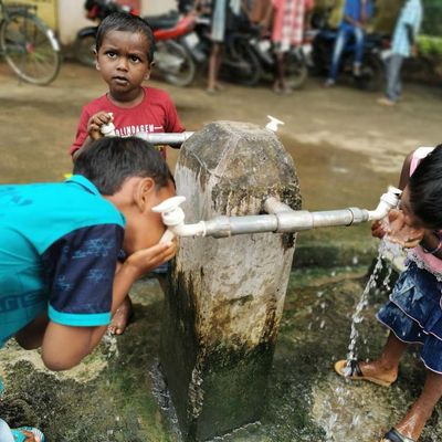 Indien: Kinder trinken Wasser aus einem Wasserhahn