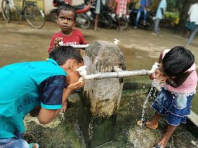 Indien: Kinder trinken Wasser aus einem Wasserhahn