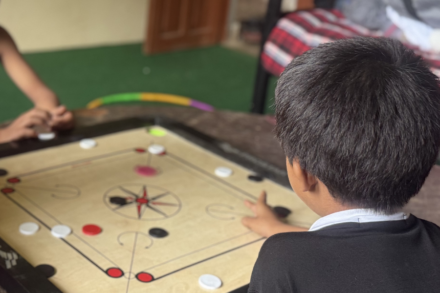 ein kleiner Junge sitzt mit dem Rücken zur Kamera und spielt ein Brettspiel