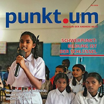 Titelbild des Magazins punkt.um der ANDHERI HILFE: Ein Mädchen in Indien steht in der Schulklasse mit einem Mikrofon in der Hand uns spricht zu den Mitschülerinnen 
