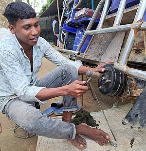 Rahim wird Mechaniker. Der jnge mann aus Bangladesch sitzt an einer Motor-Rikscha, die er repariert.