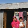 Frau mit Kind vor einem Haus in Bangladesch