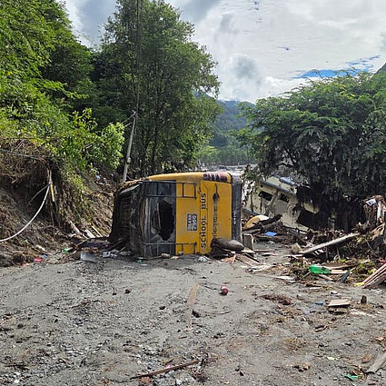 Nach der Sturzflut in Nepal: Ein auf der Seite liegender gelber Bus