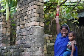 Indien: Frau mit Kind auf dem Arm im Garten